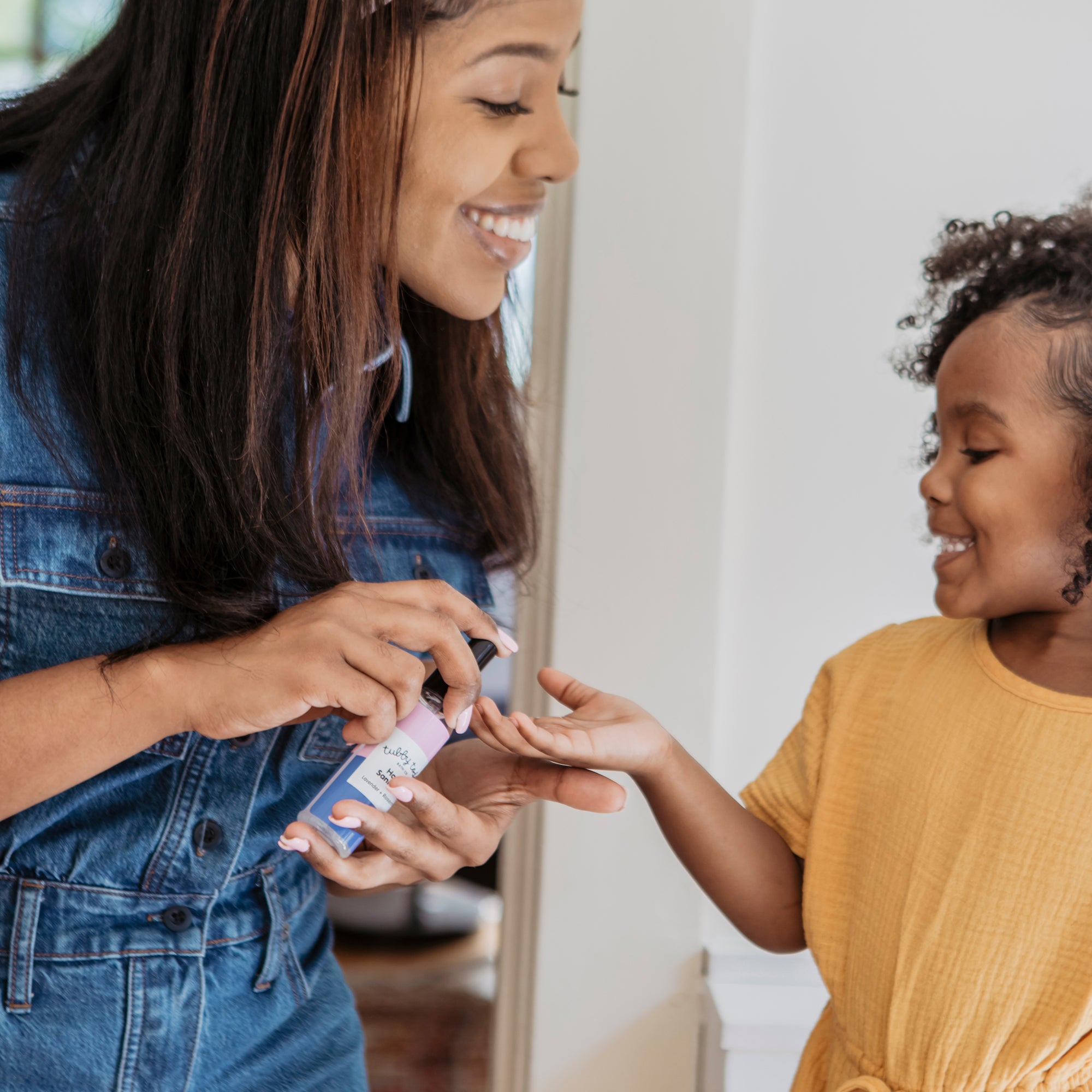 mama spraying some hand sanitizer onto her kid's hand